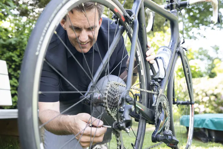 Iemand sleutelt in de tuin aan een racefiets